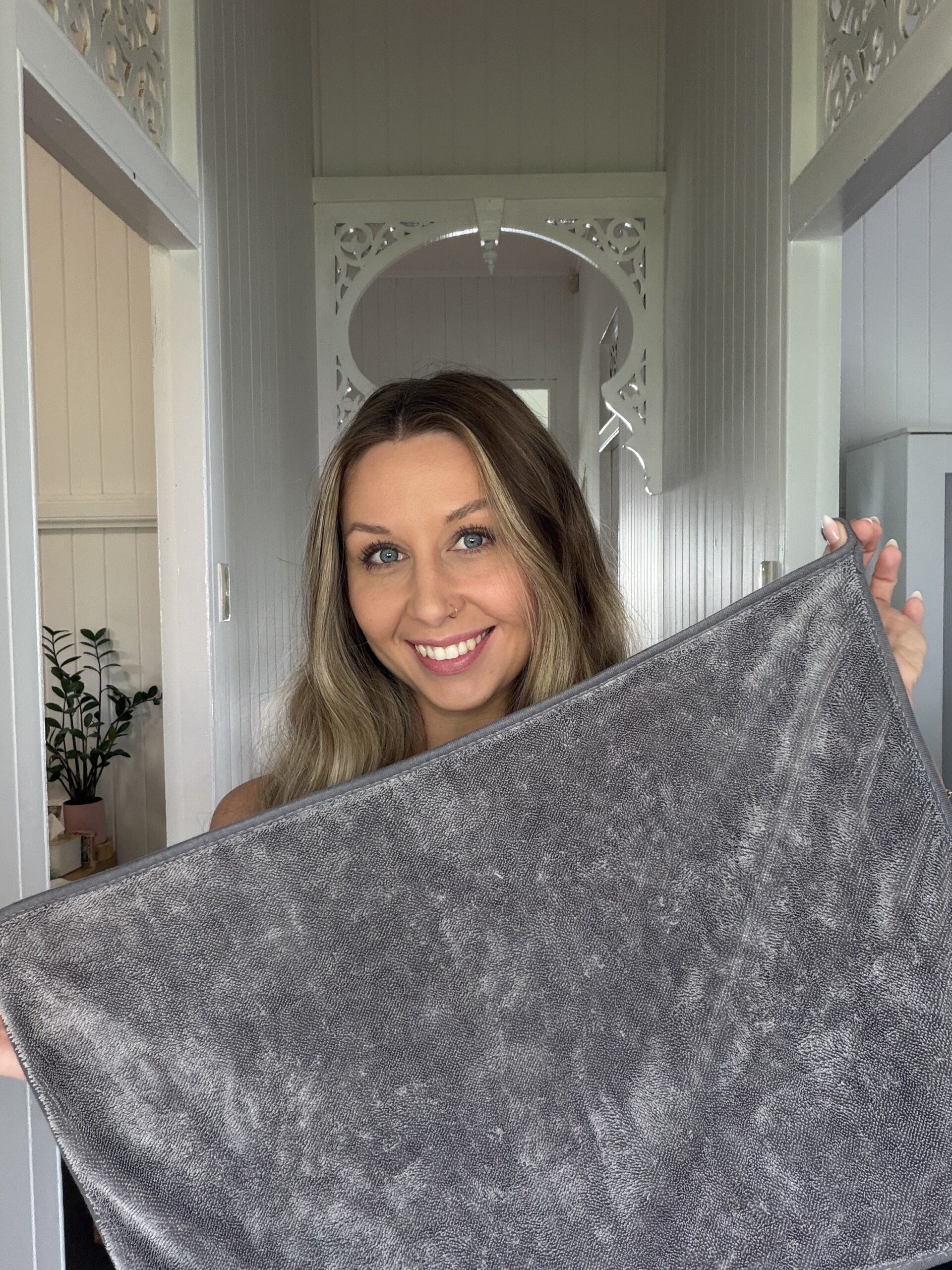 Customer holding ClothWipe in front of a spotless glass shower door